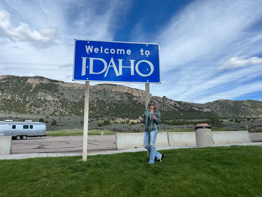 SightseeingSally stands in front of a Welcome to Idaho sign at a rest area off I-15 in Southern Idaho.